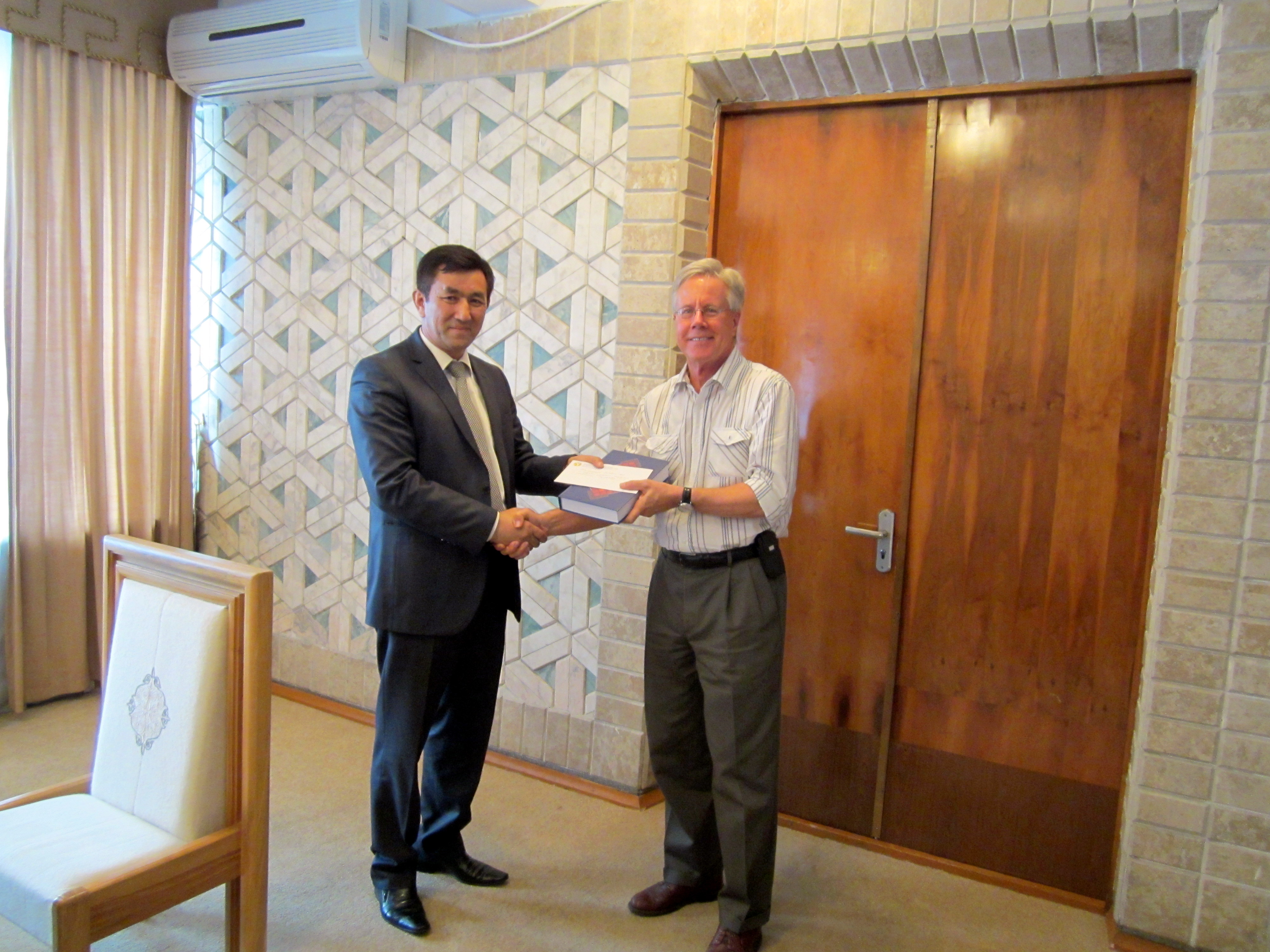 Chair Toktogul Tumanov and TSPC Director Rodger Dillon shaking hands